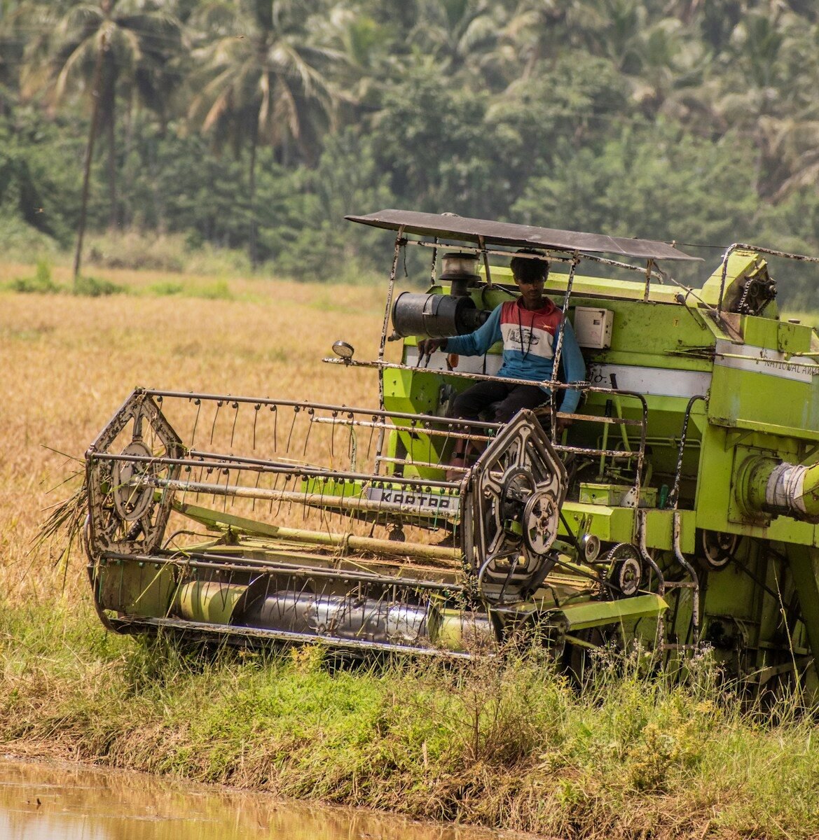 a man driving a green combine in a field